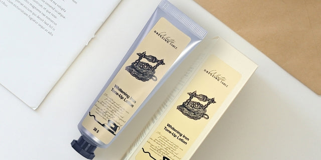 DRESSINGTABLE Brightening Iron Tone-Up Lotion packaging featuring a stylish tube and box on a desktop.