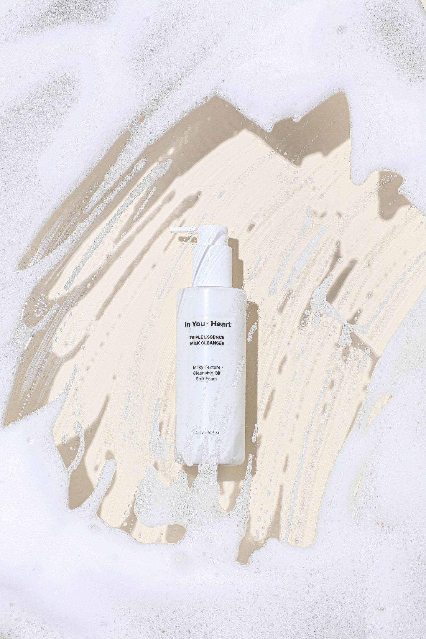 IN YOUR HEART Triple Essence Milk Cleanser bottle on a creamy foam background, showcasing its multi-texture formula.