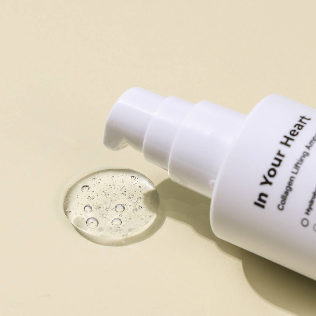 IN YOUR HEART Triple Essence Milk Cleanser with pump and liquid drop on a light background.