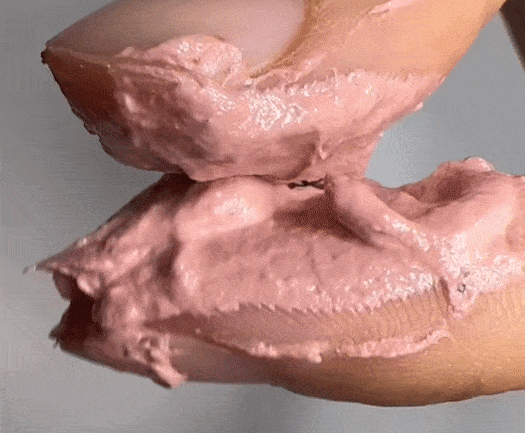 A hand with Erigeron Gelato Exfoliating Pack applied, highlighting the smooth, pink, creamy texture for gentle exfoliation and nourishment.