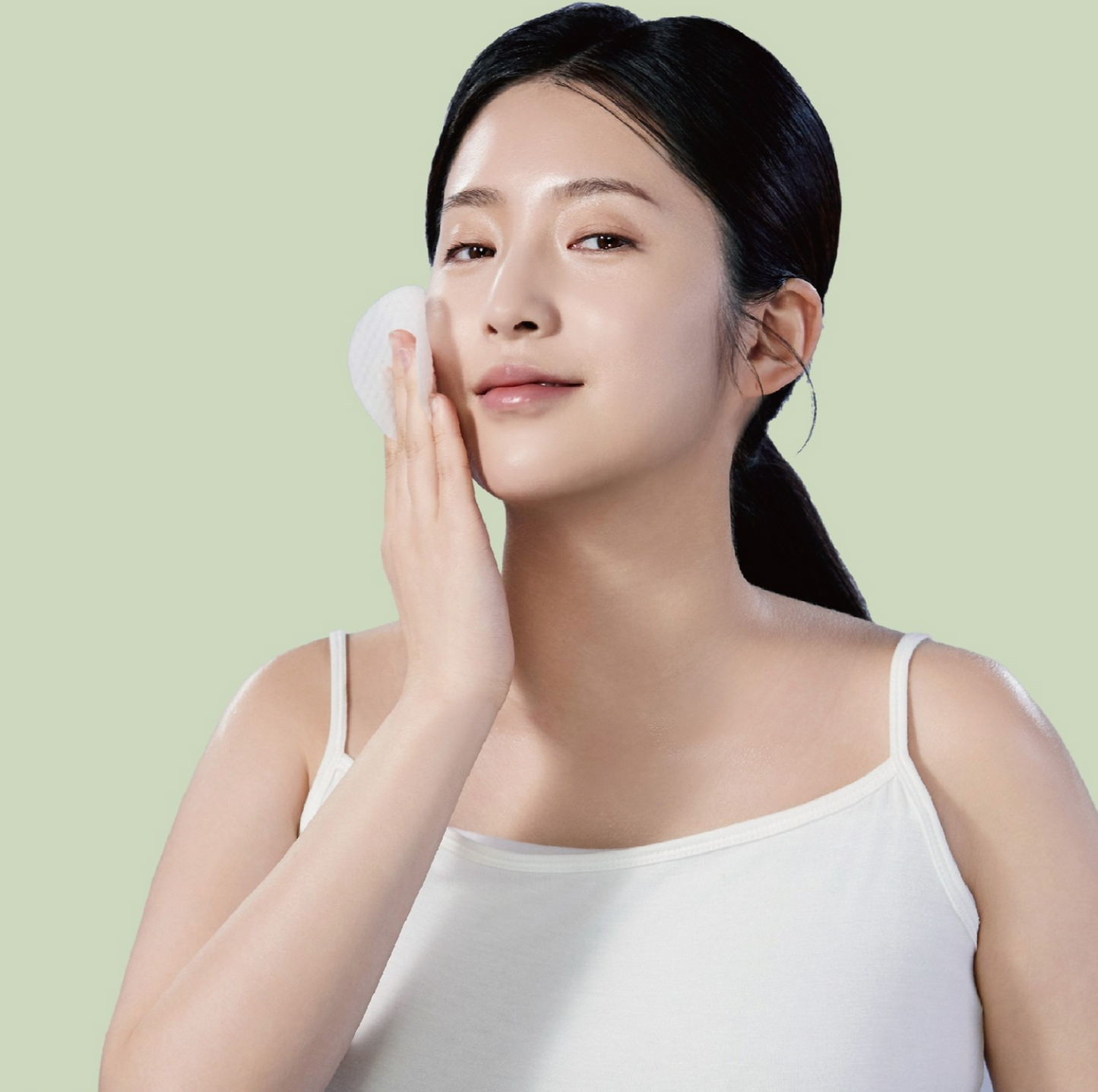 Woman using KOLEUR Collagen Toner Pad on her face for hydration and skincare.