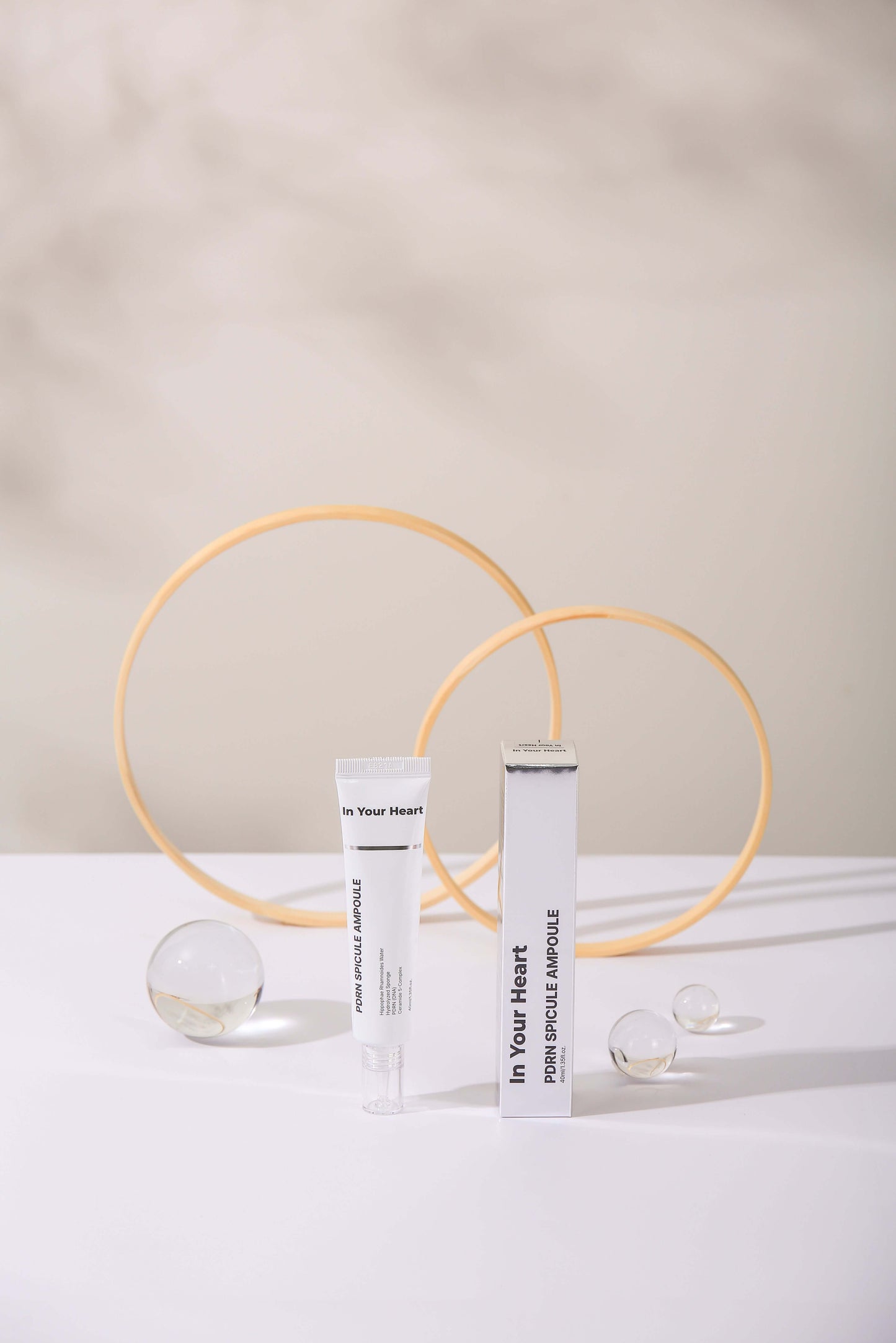 IN YOUR HEART PDRN Spicule Ampoule displayed on a minimalist table with decorative spheres and rings.