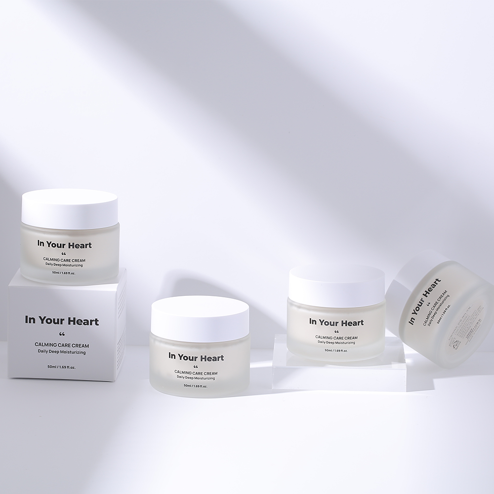 Multiple jars of 'In Your Heart Calming Care Cream' arranged on a reflective surface under soft lighting, highlighting the product's clean and simple design.