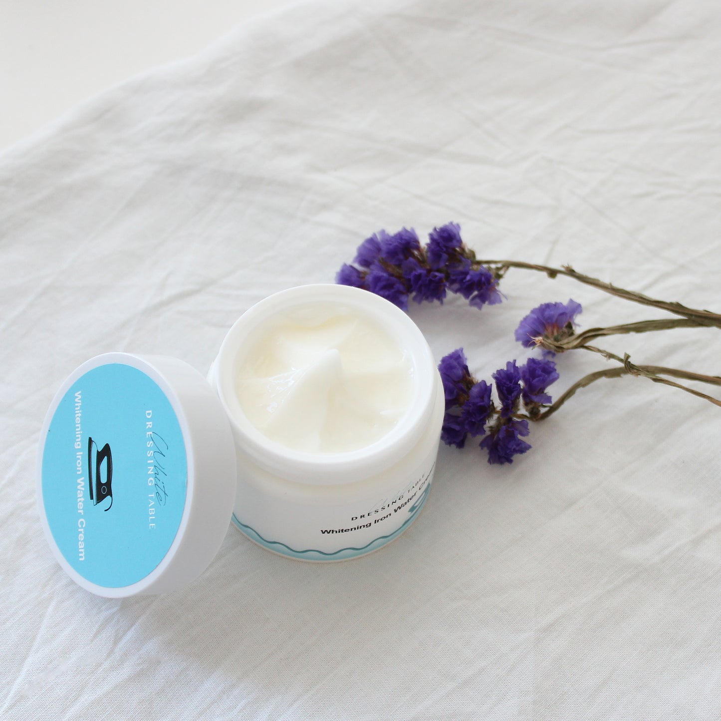 DRESSINGTABLE Brightening Iron Water Cream in a jar with flowers on a light background.