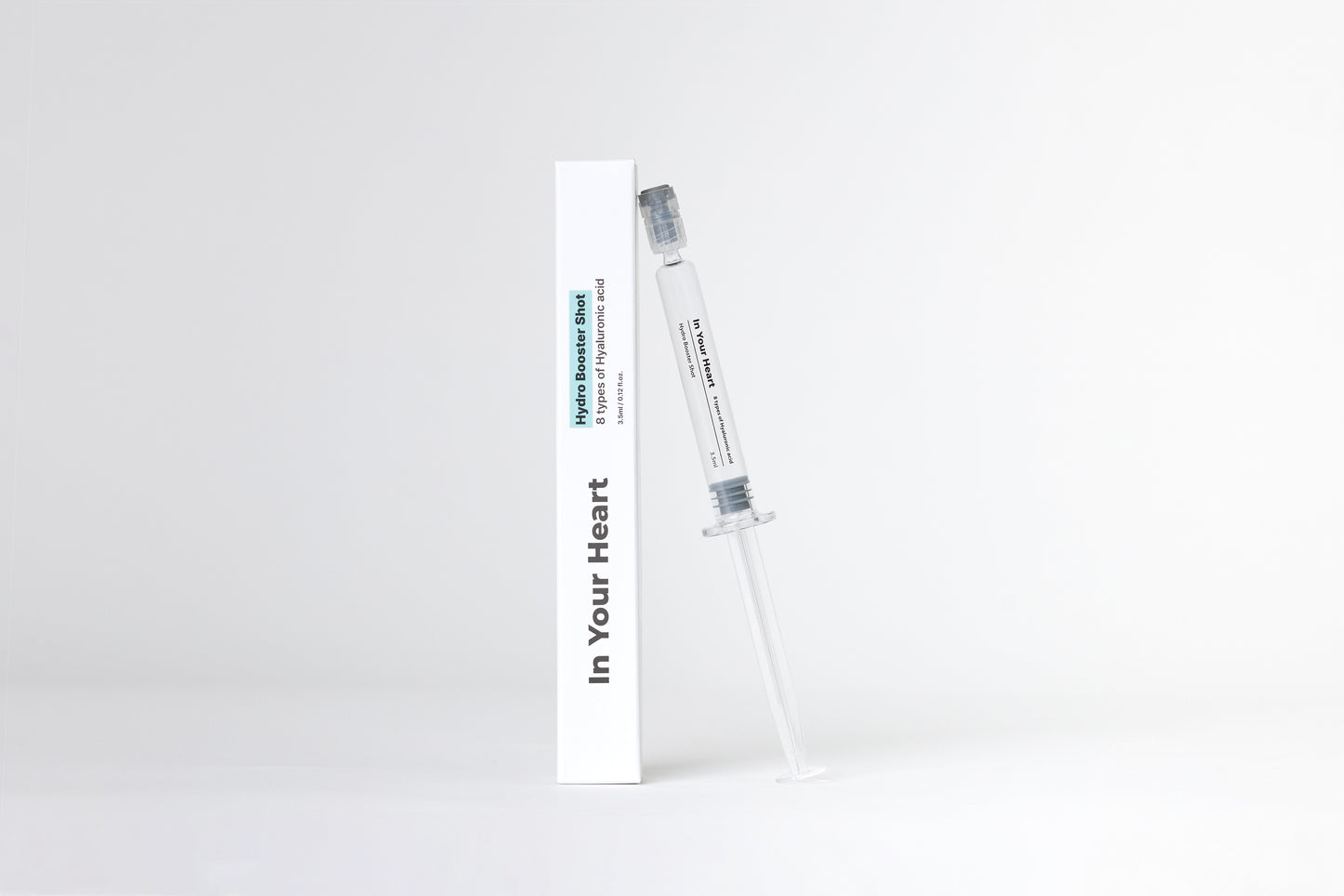 IN YOUR HEART Hydro Booster Shot in a clear syringe next to its packaging on a white background.