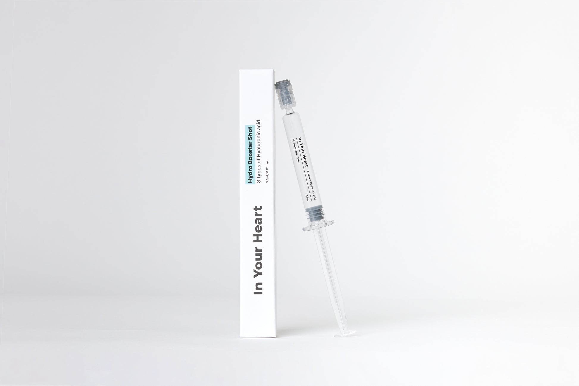 IN YOUR HEART Hydro Booster Shot in a clear syringe next to its packaging on a white background.