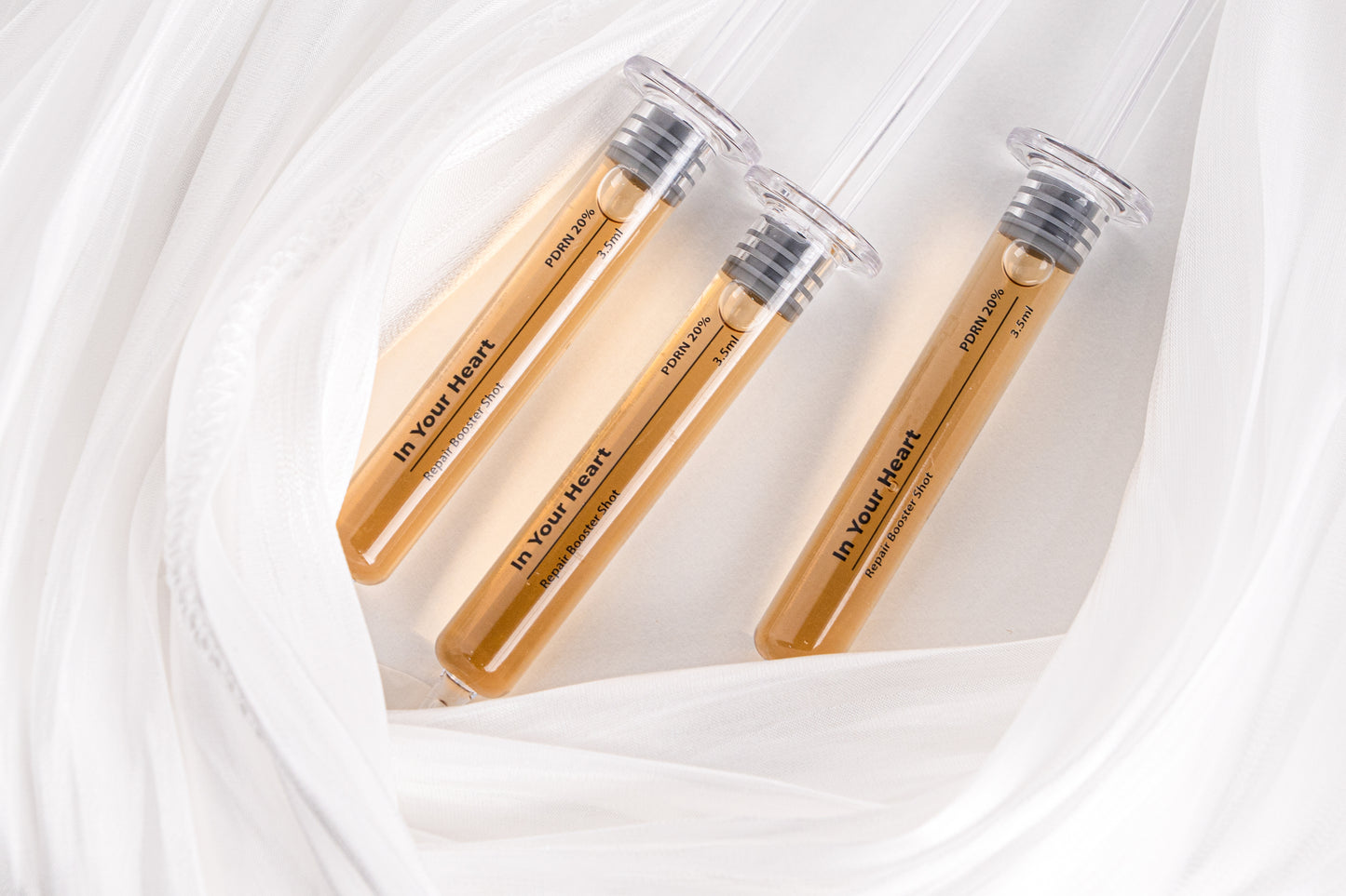 IN YOUR HEART Repair Booster Shot ampoules arranged on soft fabric background