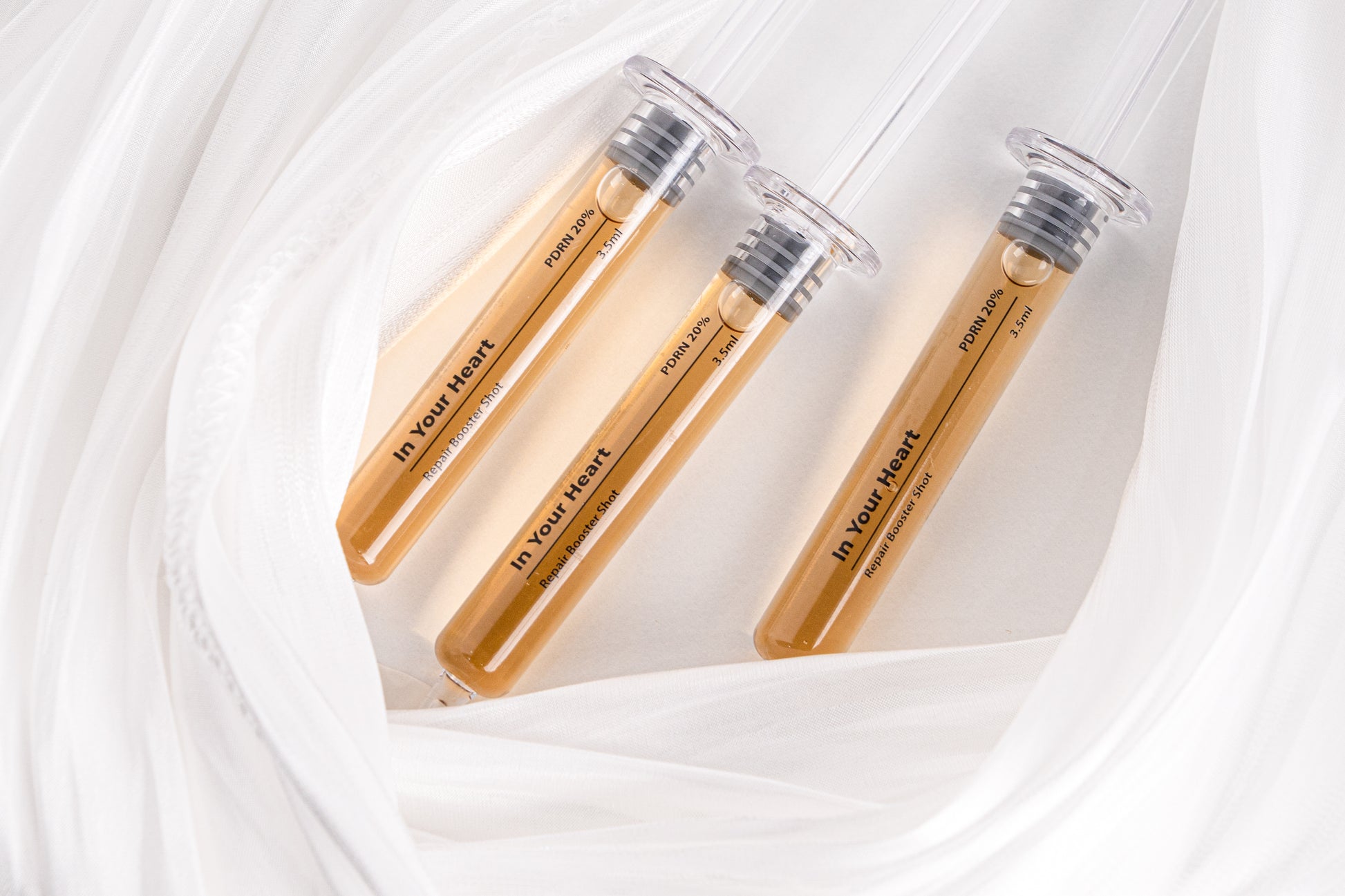 IN YOUR HEART Repair Booster Shot ampoules arranged on soft fabric background