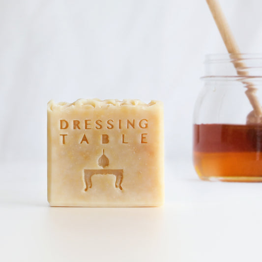 Honey colored bar soap with "dressing table" written on it and real honey in a jar next to it.