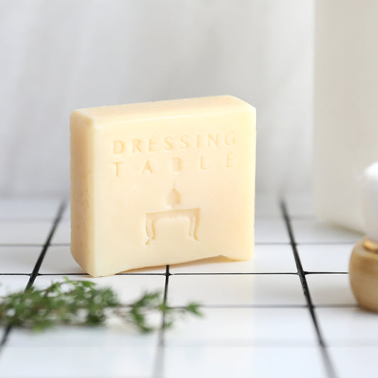 Cream colored bar soap with "dressing table" written on it on top of white tiles