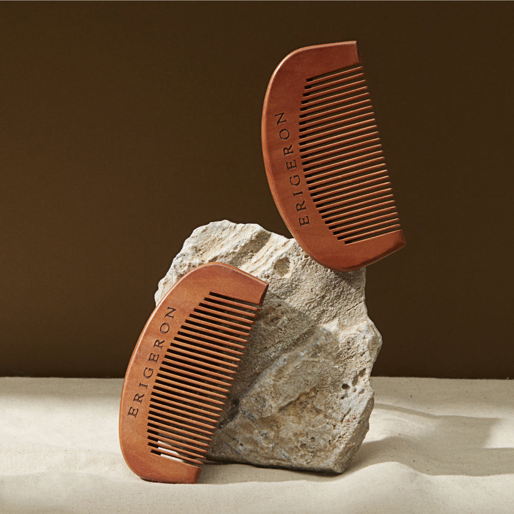 Two Erigeron Natural Wooden Combs displayed in dark brown next to a white rock