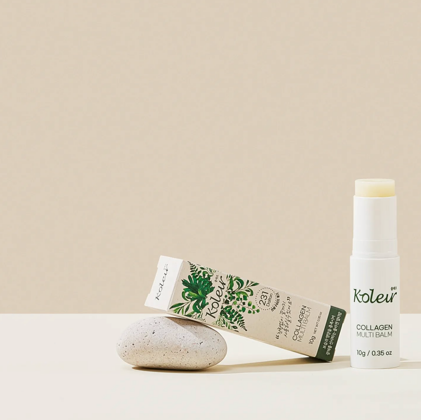 Koleur Collagen Multibalm stick placed next to its packaging on a beige surface with a minimalist design, emphasizing its sleek and portable format.