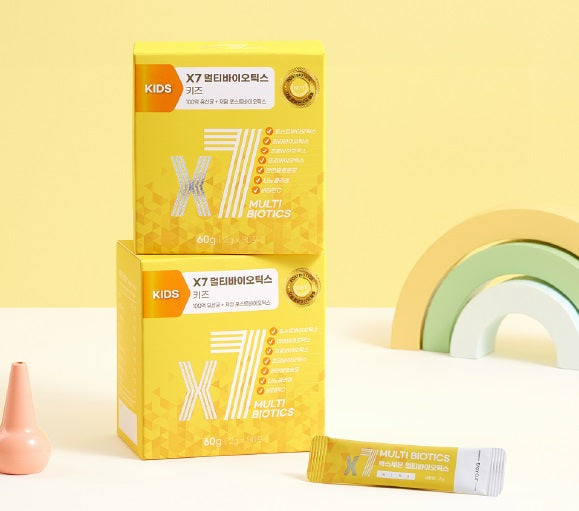 A vibrant yellow box of X7 Kids Multi Biotics, designed for children’s gut health, displayed with a rainbow-colored decor in the background and a single biotics stick sachet in front.