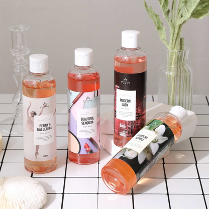 four bottles of body wash in peach and pink colors on tile floor