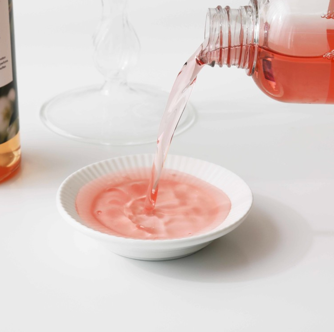 red liquid coming out of bottle into a white dish