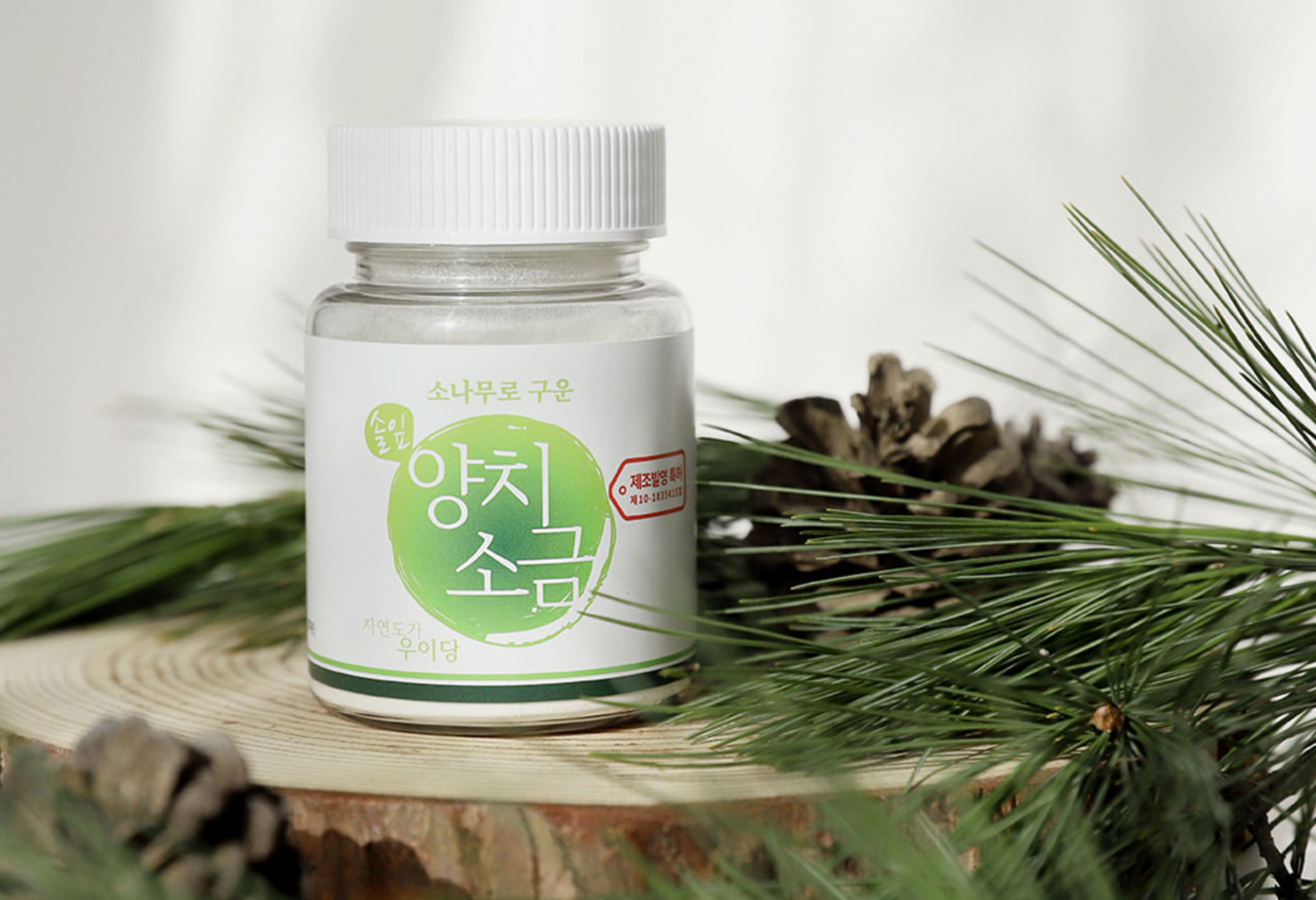 bottle with white cap next to pine cone and pine needles