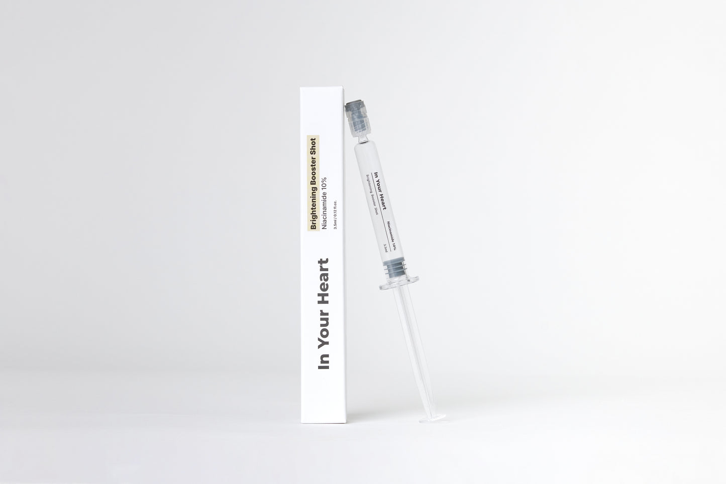 IN YOUR HEART Brightening Booster Shot in a syringe and box, designed to brighten and enhance skin radiance.