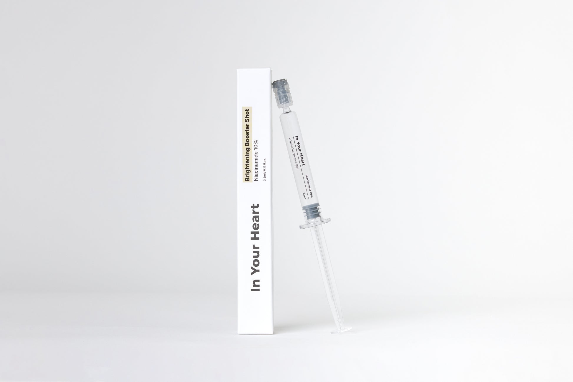 IN YOUR HEART Brightening Booster Shot in a syringe and box, designed to brighten and enhance skin radiance.