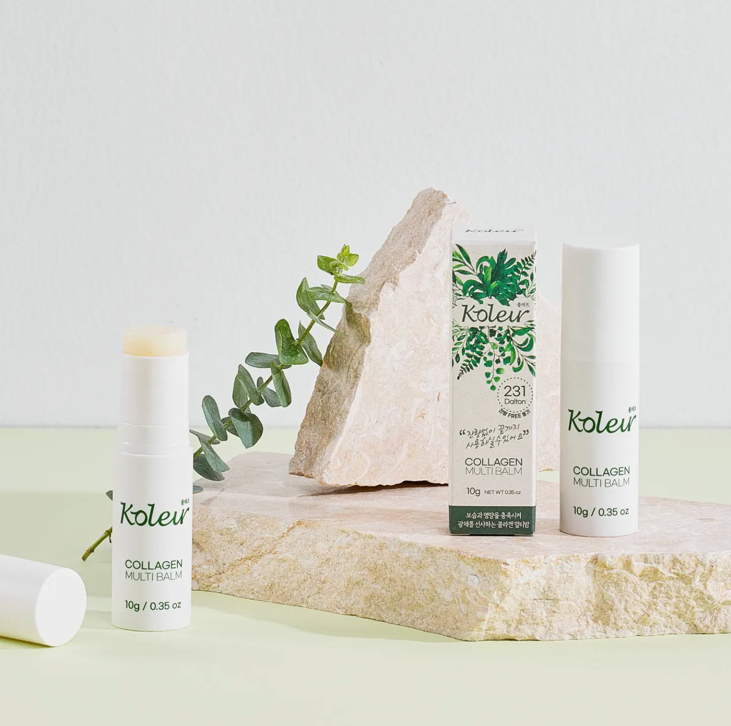 Koleur Collagen Multibalm stick and packaging styled on a rock with eucalyptus leaves, showcasing its natural ingredients and elegant presentation.
