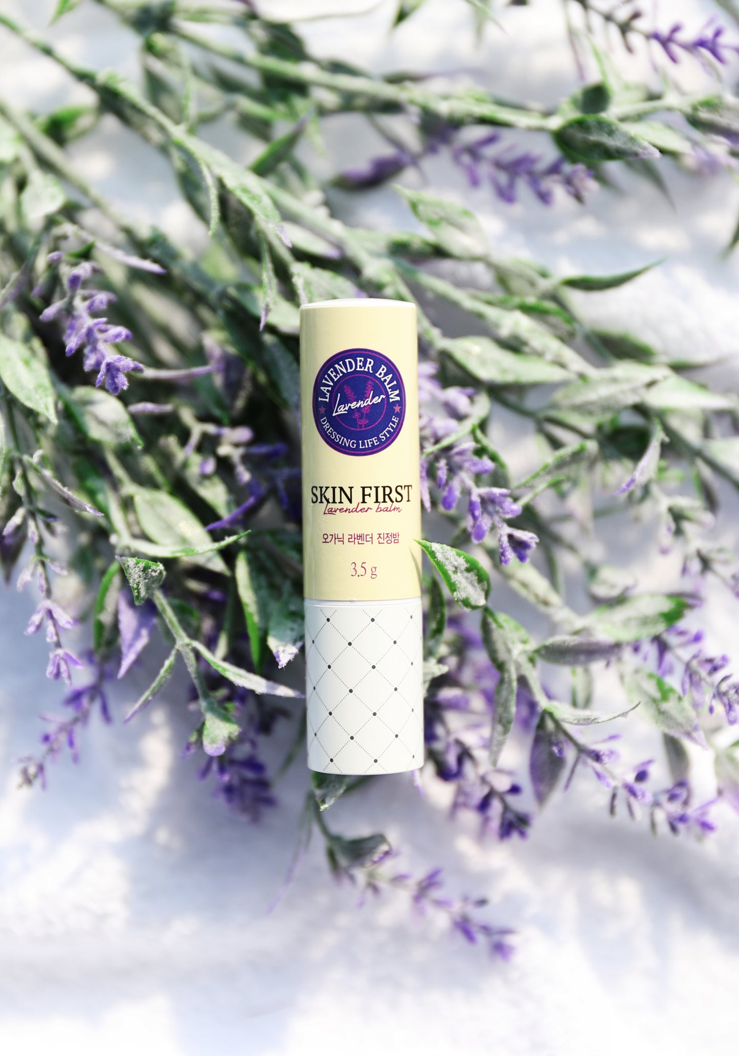  The balm is surrounded by fresh lavender flowers, highlighting its key ingredient and soothing properties. The background has a soft-focus effect, making the product the central focal point.