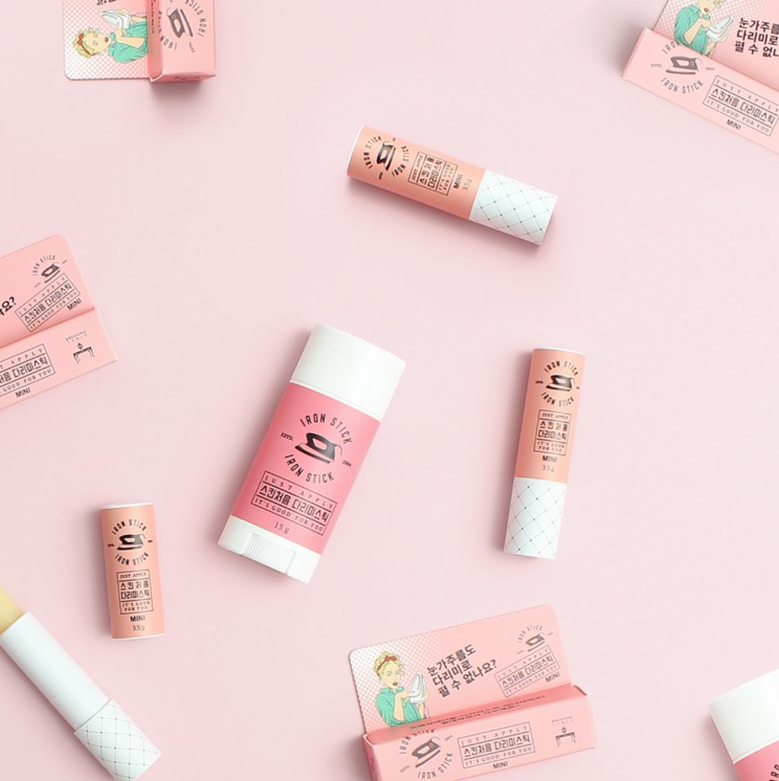 A flat lay of multiple Iron Stick products in varying sizes and designs, arranged on a pastel pink background for a stylish, cohesive display.