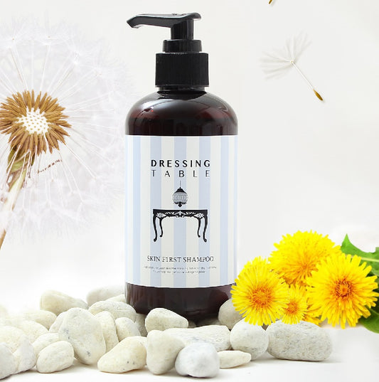 amber brown bottle of shampoo with black pump next to dandelions