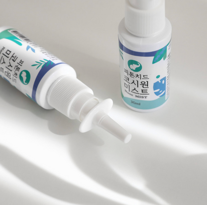 A close-up of the Phytoncide Nasal Mist Spray bottle (30ml) lying on a white surface, with its nozzle clearly displayed. The product features a clean, modern design with green and blue accents on the label.